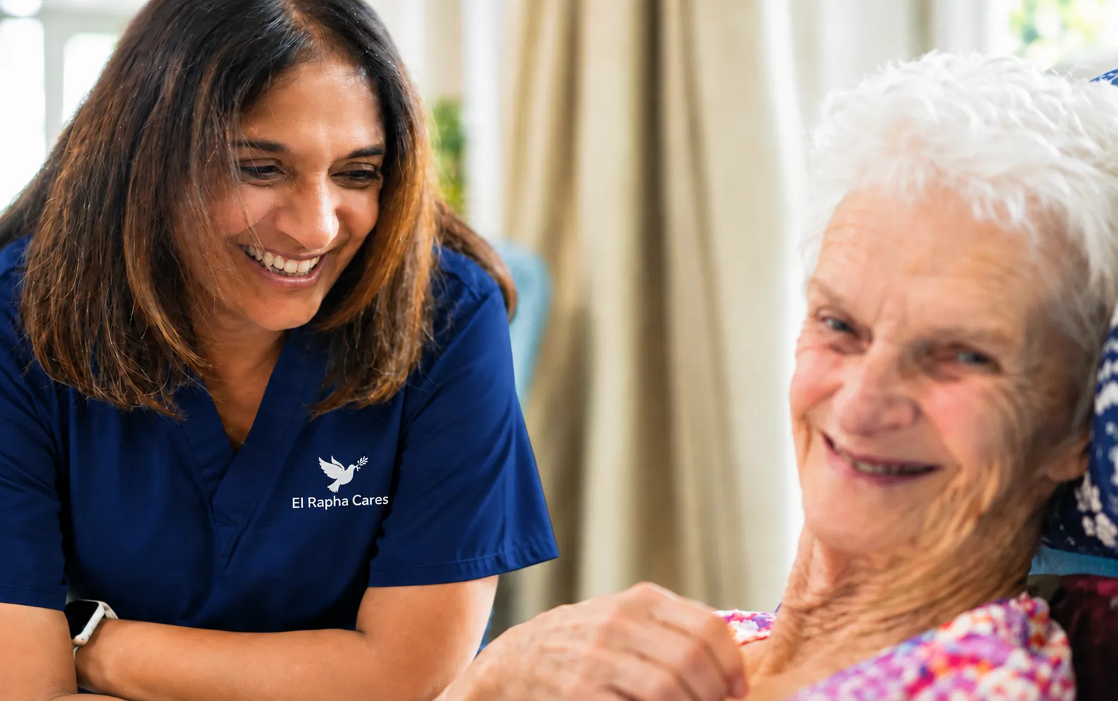 El Rapha Cares carer smiling beside an elderly woman